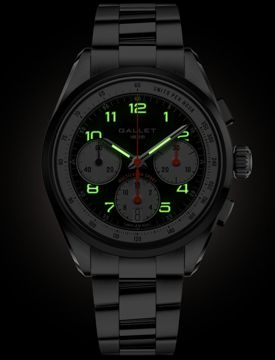 Black stainless steel chronograph watch with green luminous numerals and three subdials on a dark dial.
