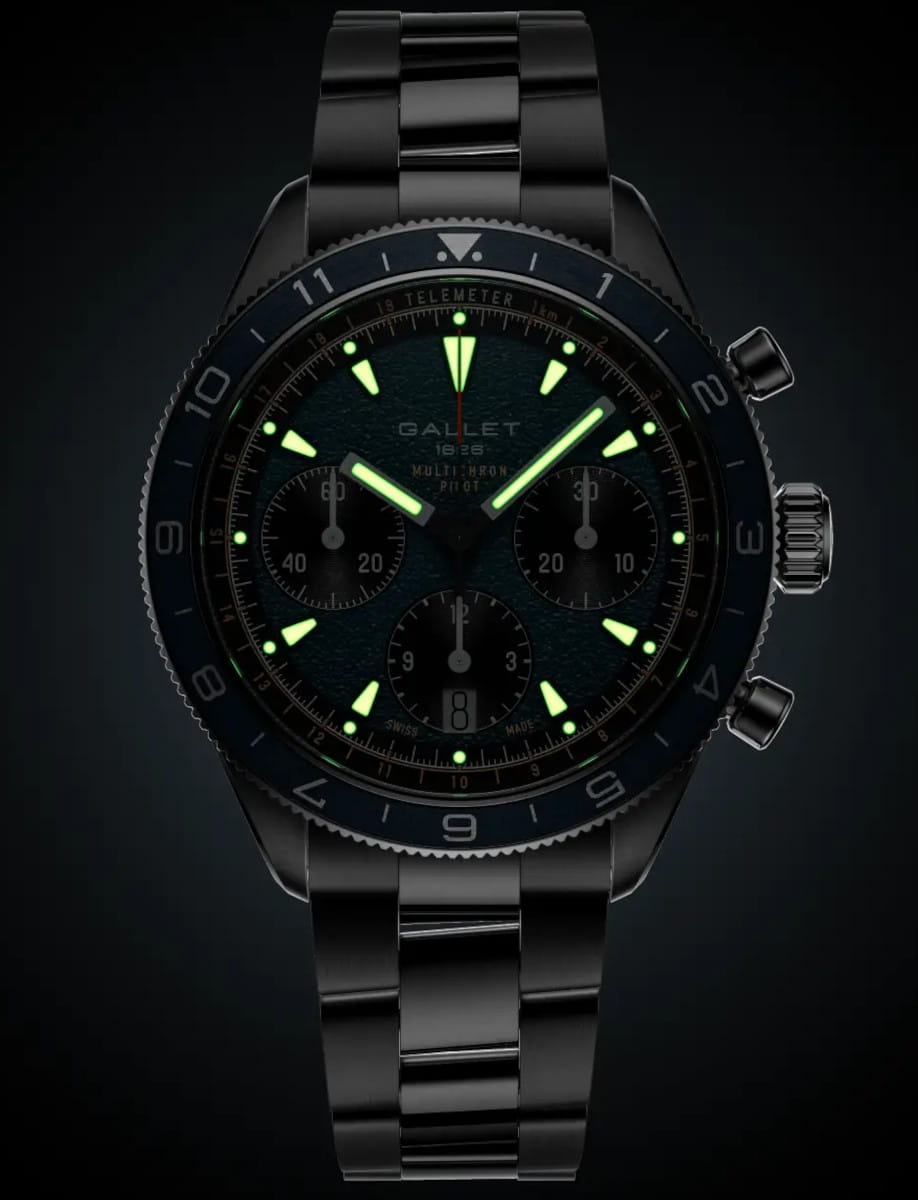 Stainless steel Gallet chronograph wristwatch with glowing green hands and hour markers, three sub-dials, and a date window at 6 o'clock on a steel bracelet