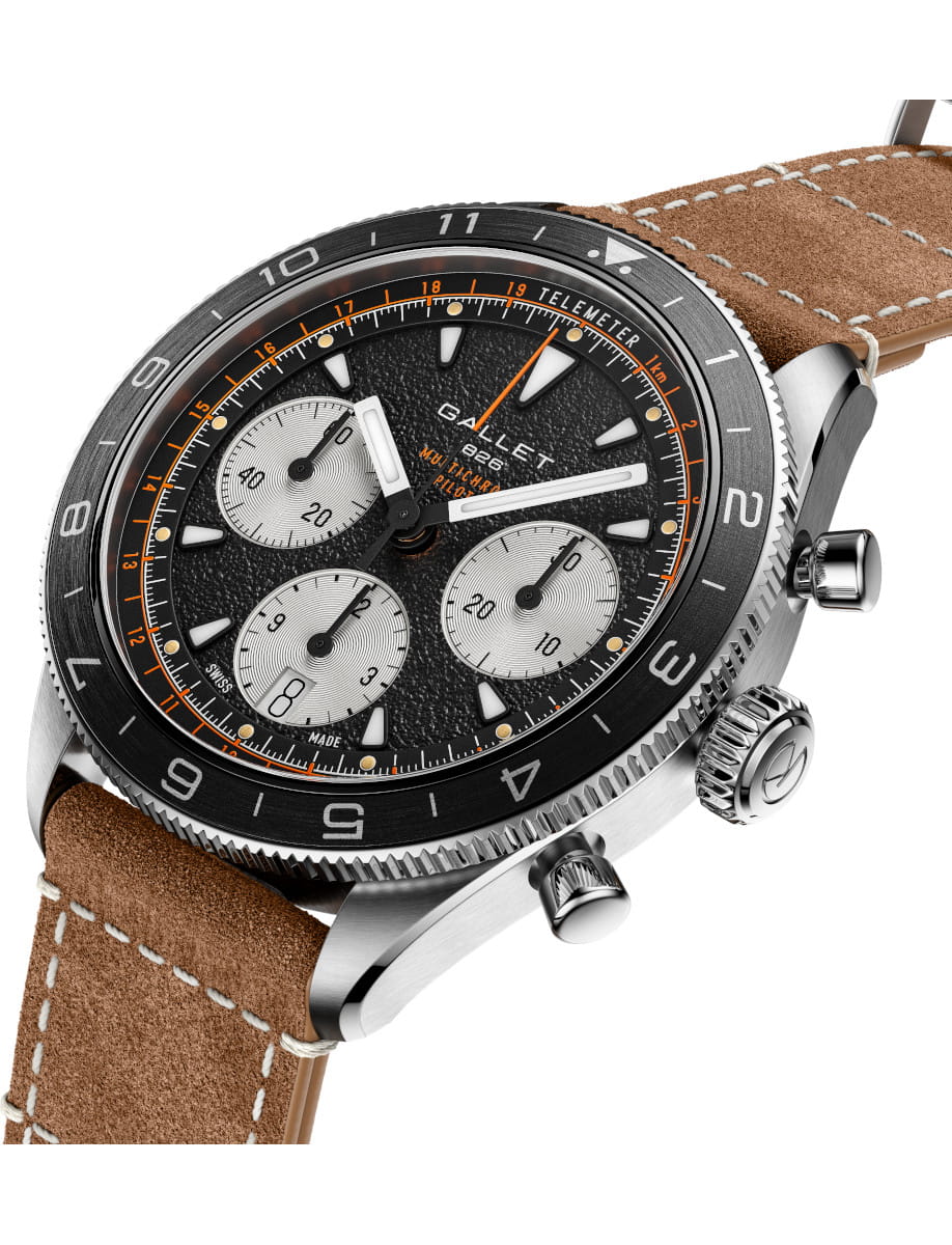 Close-up of a black chronograph wristwatch with three silver subdials, orange accents, and a brown leather strap.