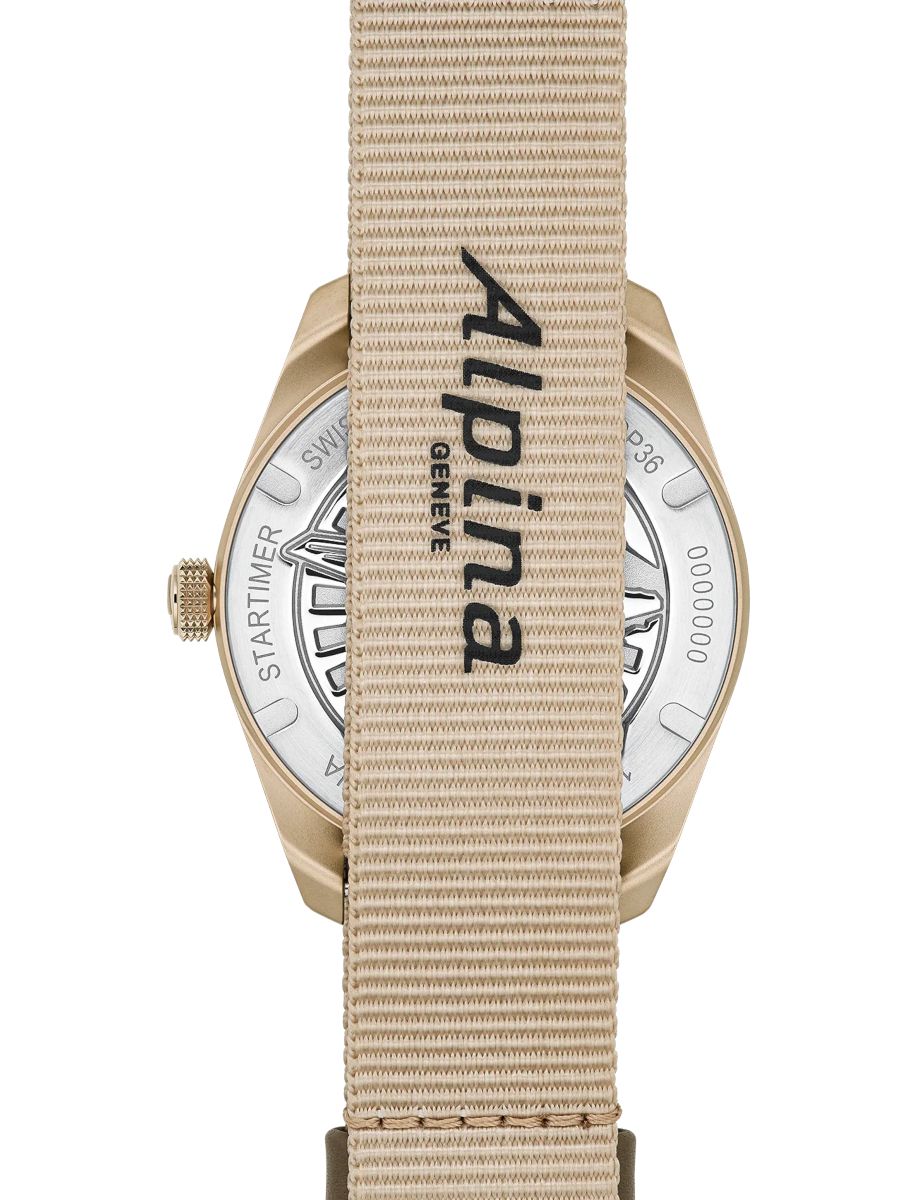 Close-up of a gold wristwatch with a beige fabric strap running vertically, revealing the metal case back and crown.