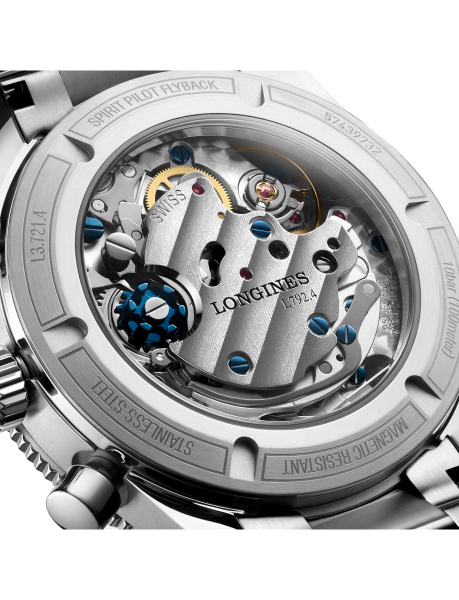 Close-up of a Longines watch movement visible through the transparent case back, showing gears and blue screws in a stainless steel finish.