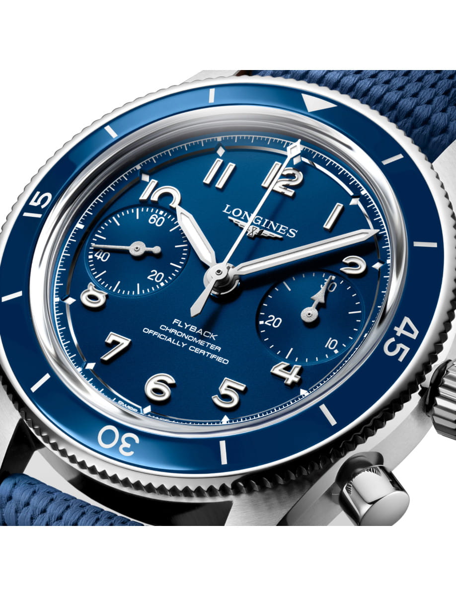 Close-up of a Longines wristwatch with blue dial, stainless steel case and ceramic bezel, and blue fabric strap.