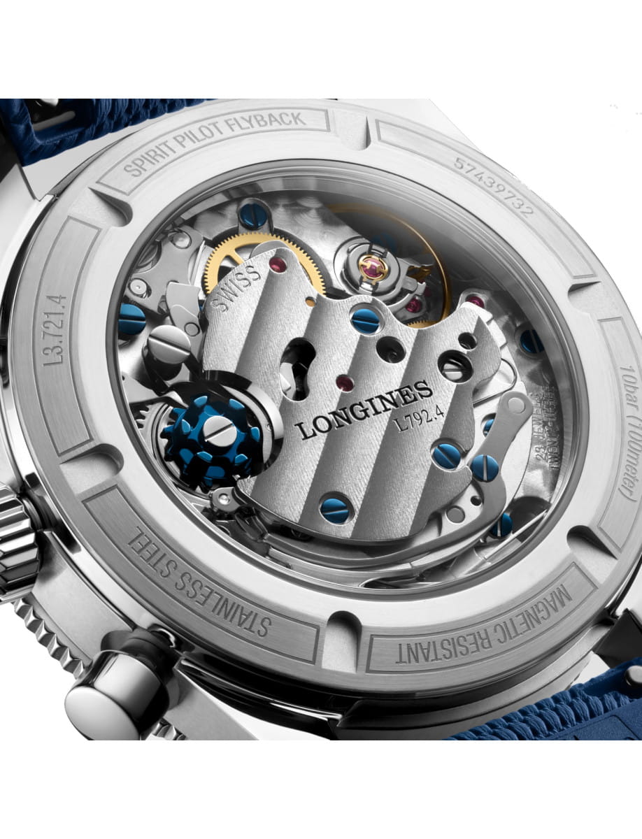 Close-up of a Longines watch movement seen through the transparent case back, showing gears, blue screws, and engraved text.