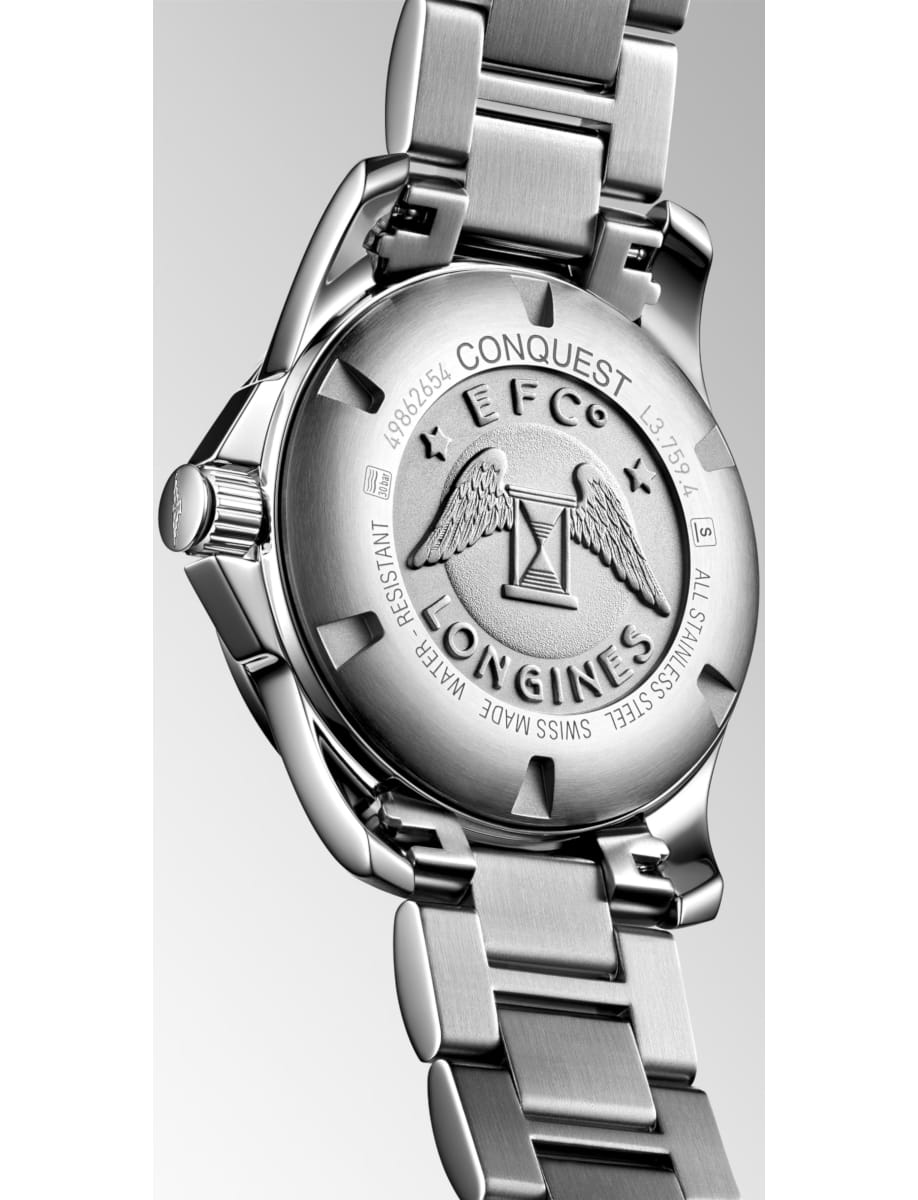 Close-up of a silver Longines Conquest wristwatch case back with an engraved emblem and a brushed metal link bracelet, showing surrounding inscriptions and stainless steel finish.