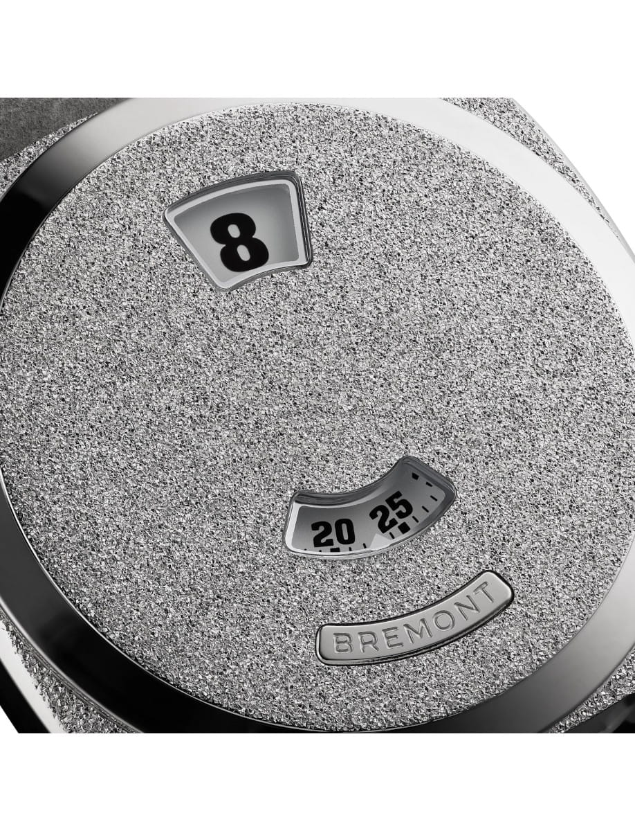 Close-up of a stainless steel textured Bremont watch dial with an hour window showing 8 and minute 20-25.