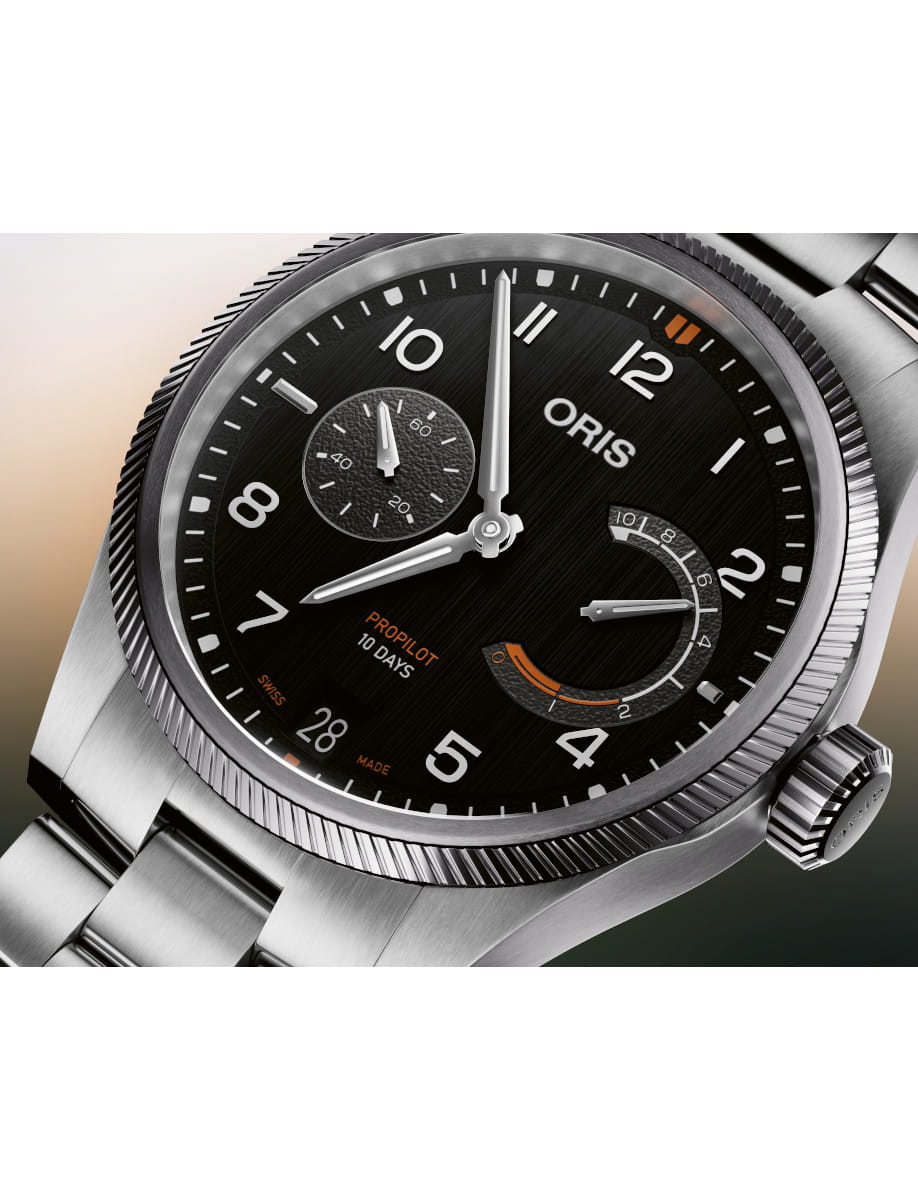 Close-up of an Oris ProPilot 10 Days wristwatch with stainless steel case and bracelet, black dial, date at 6, and a curved power-reserve indicator.