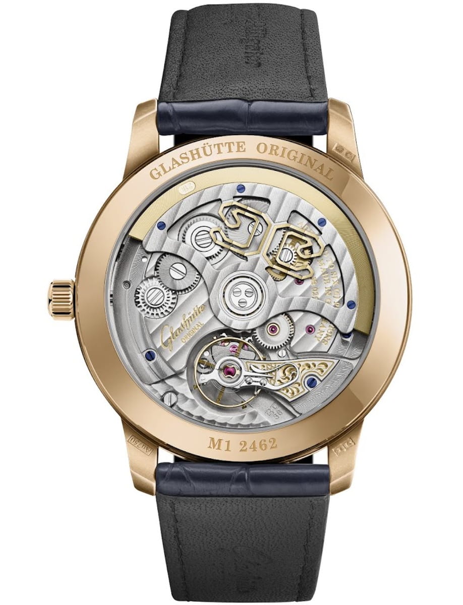 Gold wristwatch with a transparent case back showing the intricate mechanical movement