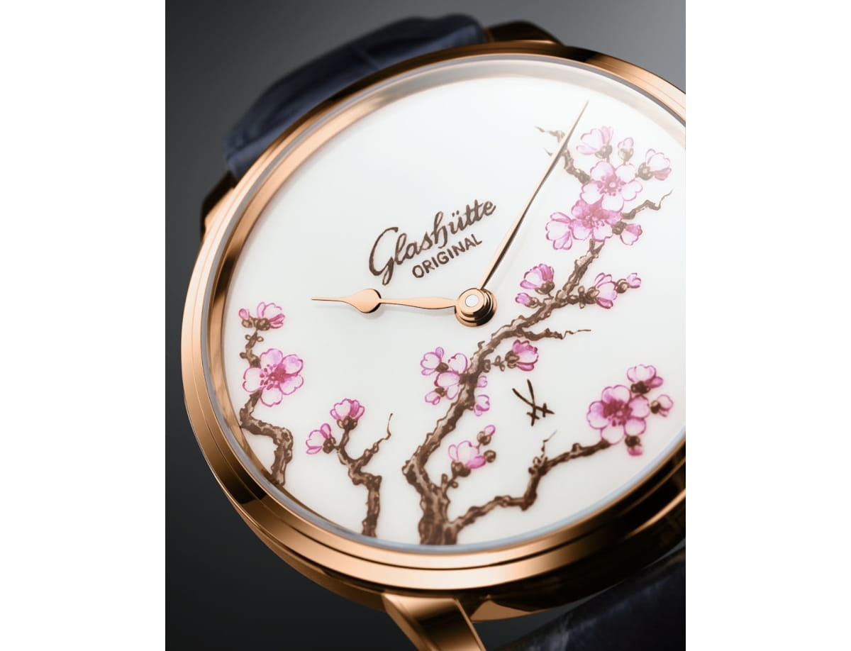 Close-up of a rose-gold Glashütte Original wristwatch with a white dial and pink blossom branches design