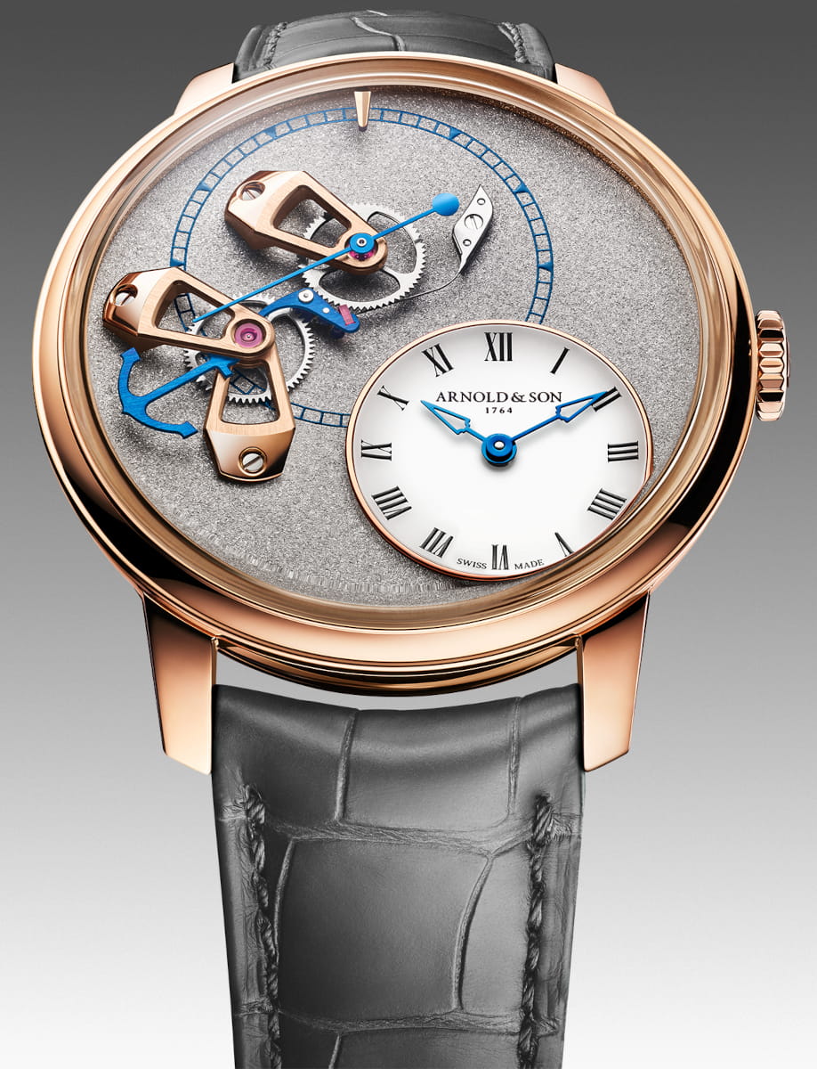 Red gold skeleton Arnold&Son watch with exposed gears, blue hands, white Roman-numeral subdial, and gray strap.