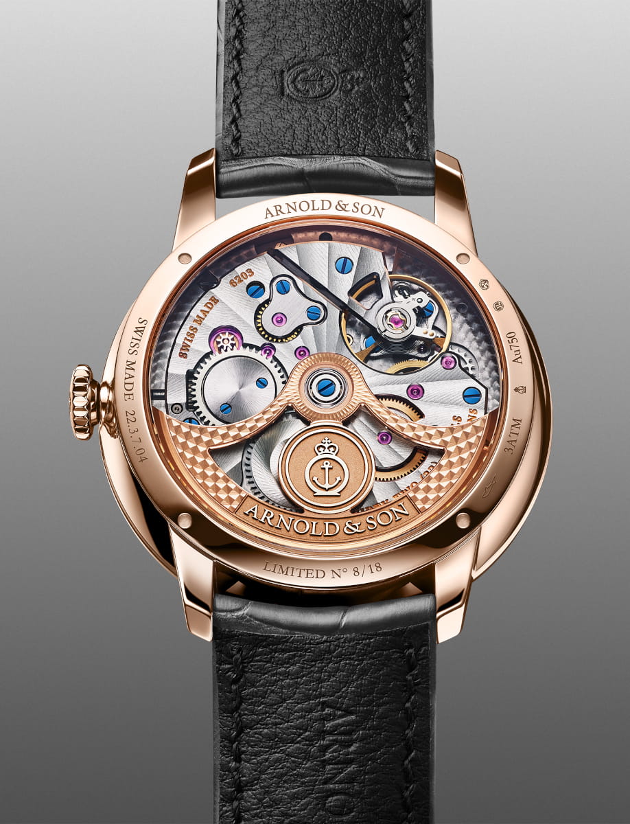 Red gold Arnold & Son wristwatch with a transparent back showing the skeleton movement, blue screws, and engraved branding; limited edition 8 of 18 with a black leather strap.
