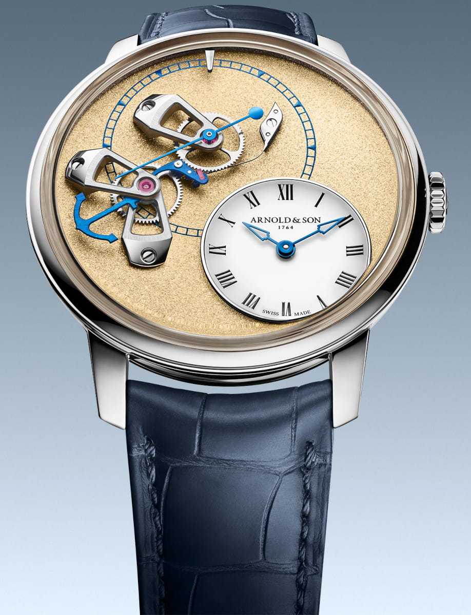 Close-up of an Arnold & Son wristwatch with a 950 platinum case, exposed movement, and a ink blue leather strap.