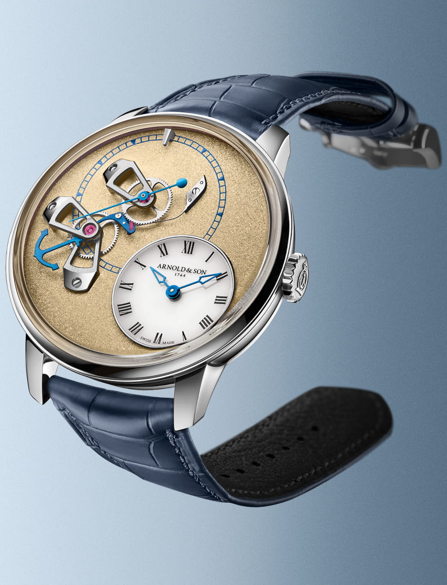Side view of Arnold & Son wristwatch with a 950 platinum case, exposed movement, and a ink blue leather strap.