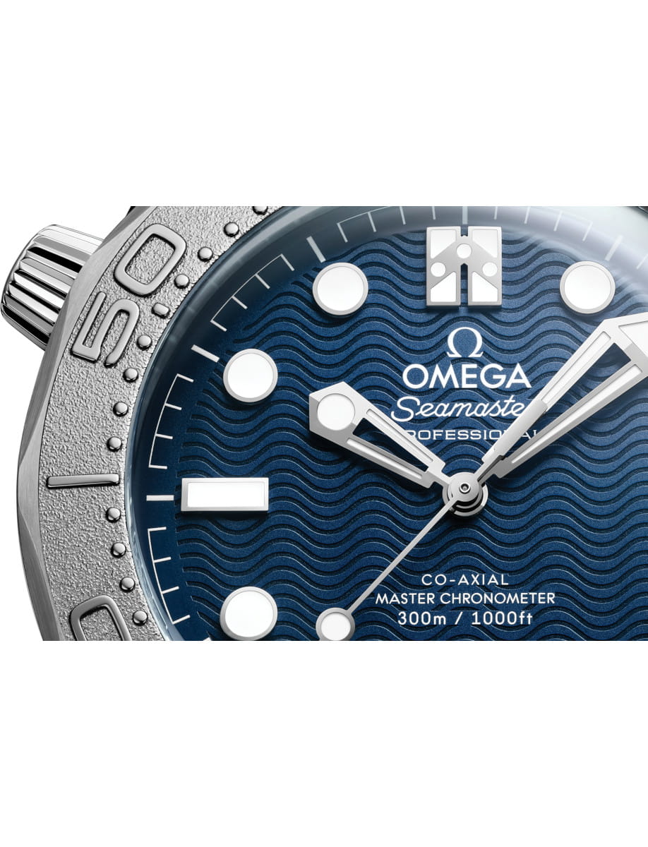 Close-up of an Omega Seamaster Professional watch face with a blue wave-pattern dial, white markers, and luminous hands.