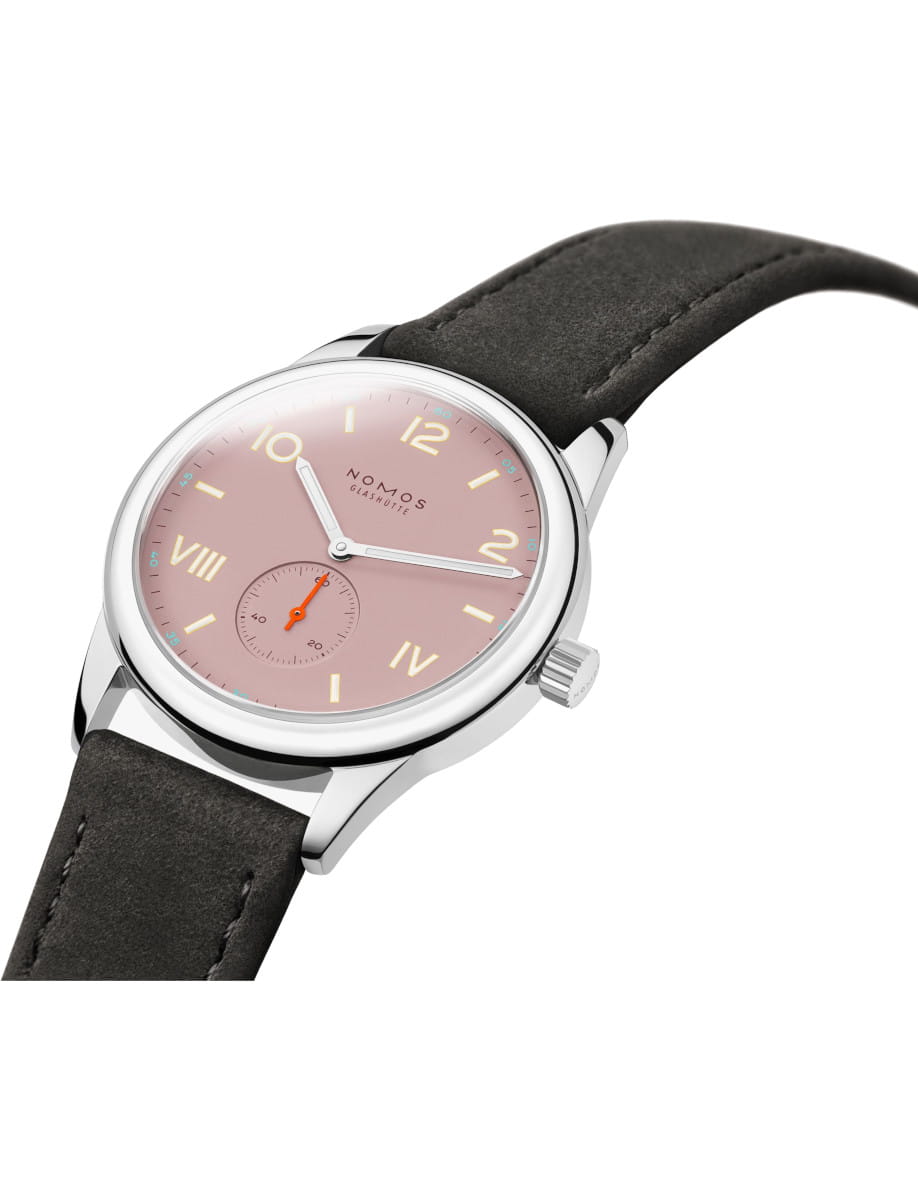 Side view of NOMOS Glashütte wristwatch with a pink dial, stainless steel case, and black leather strap.