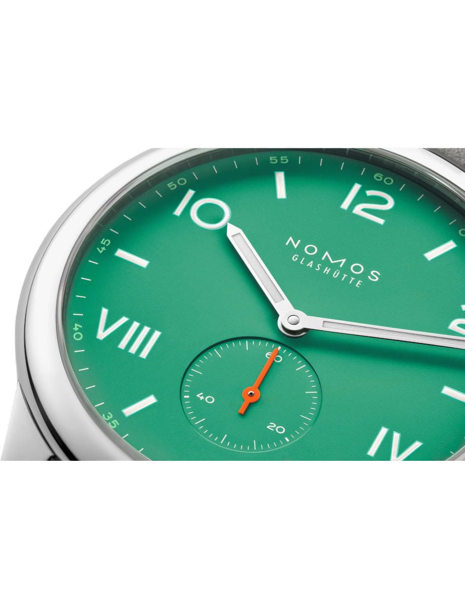 Close-up of a green NOMOS Glashütte wristwatch dial with silver hands and a small seconds subdial.