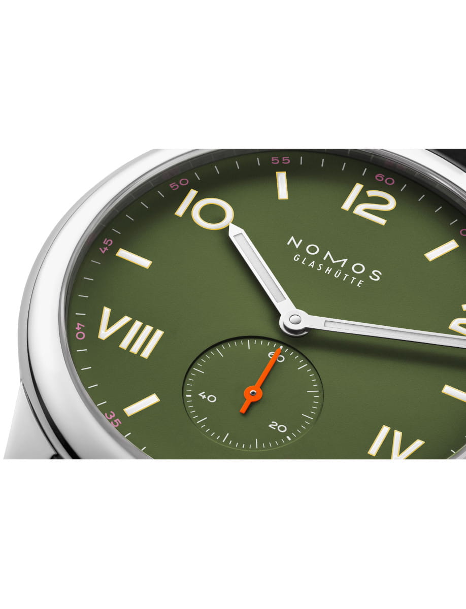 Close-up of a NOMOS Glashütte wristwatch with a green dial, Roman numerals, and red small seconds hand