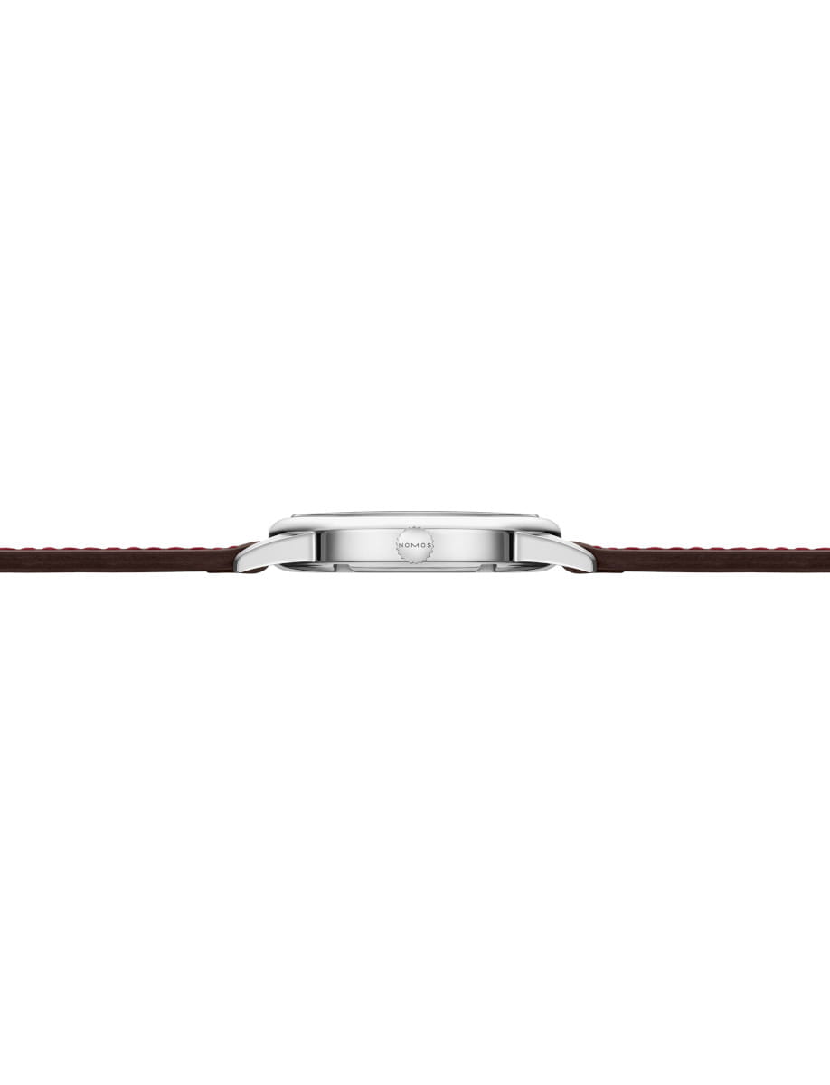 Side view of Nomos Club wristwatch with stainless steel case, Horween Genuine Shell Cordovan brown strap with red stitching.