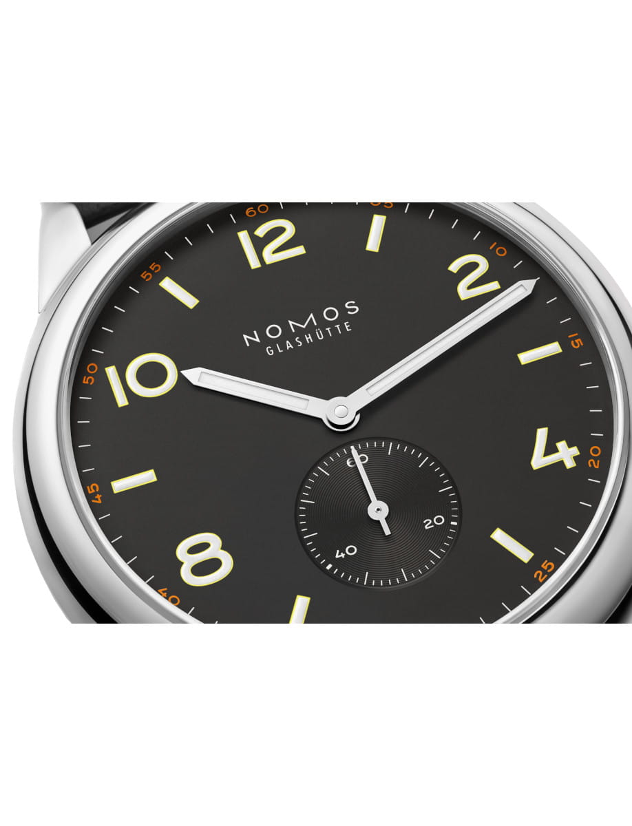 Close-up of a Nomos Club wristwatch with stainless steel case, Horween Genuine Shell Cordovan black strap with brown stitching, and black dial.