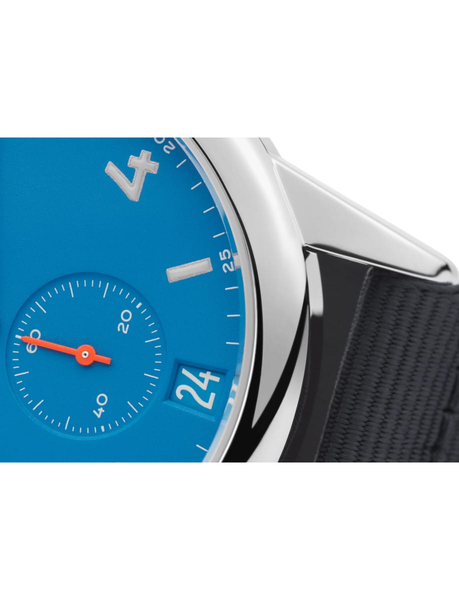 Close up of Nomos Club wristwatch with stainless steel case, blue-black textile strap, and siren blue dial.