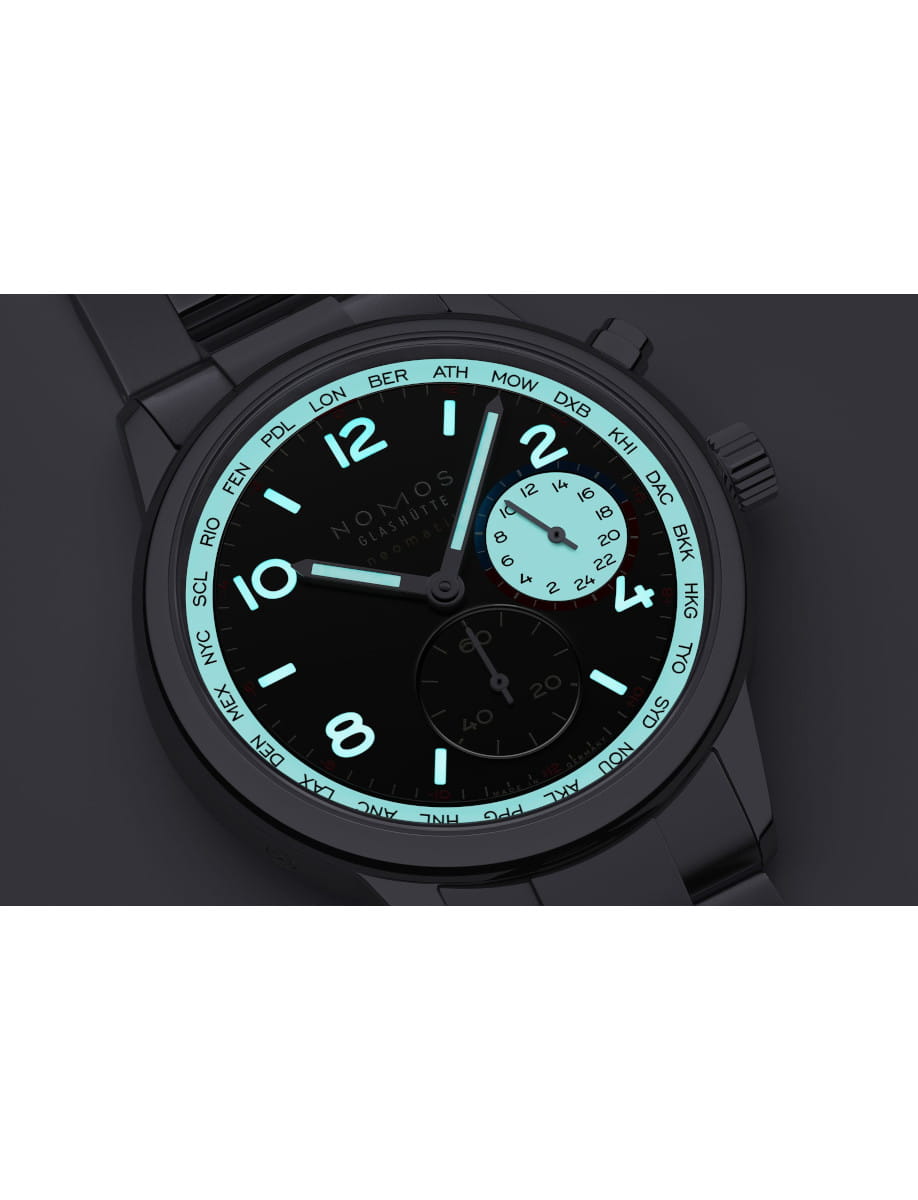 Black wristwatch with turquoise luminescent numerals and a world-time city ring around the dial (Nomos Glashütte).