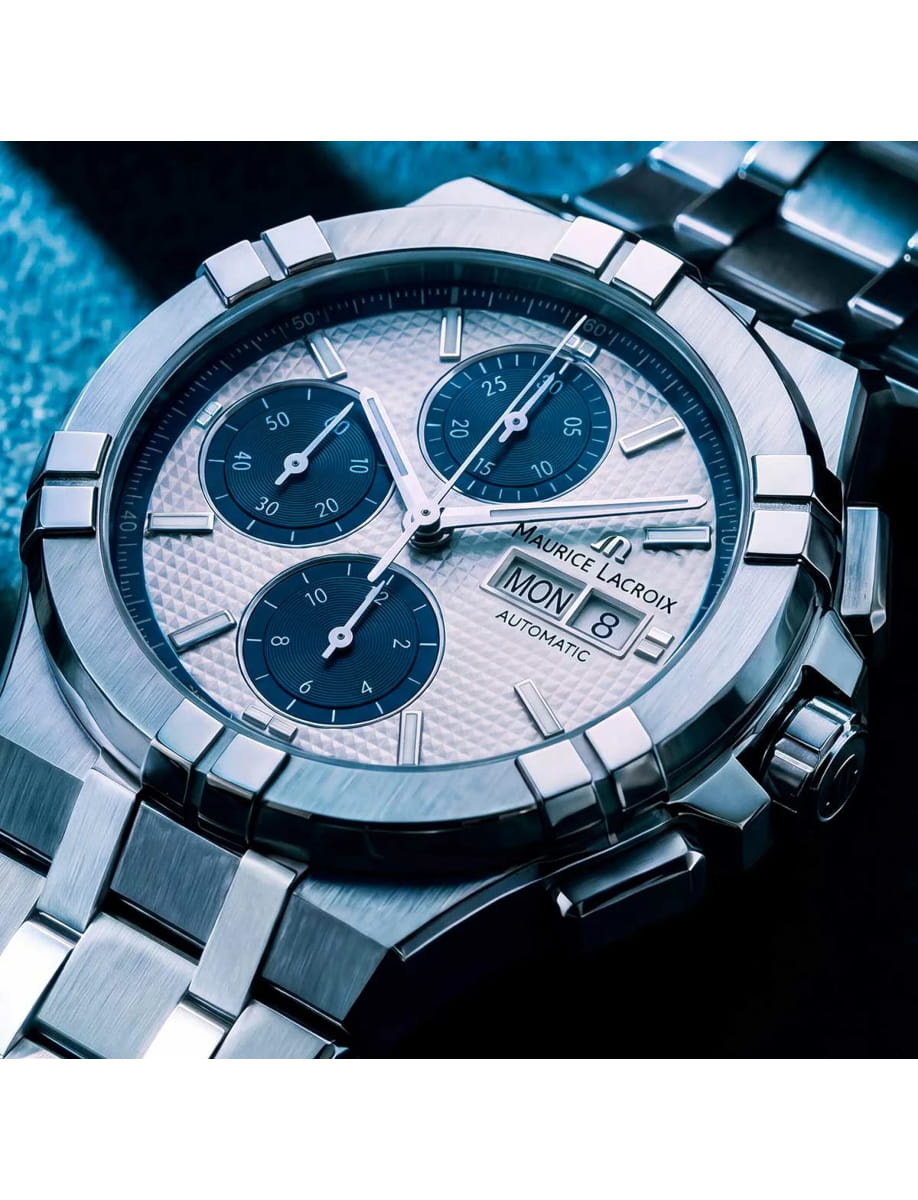 Close-up of a silver Maurice Lacroix chronograph watch with blue subdials and day/date display.