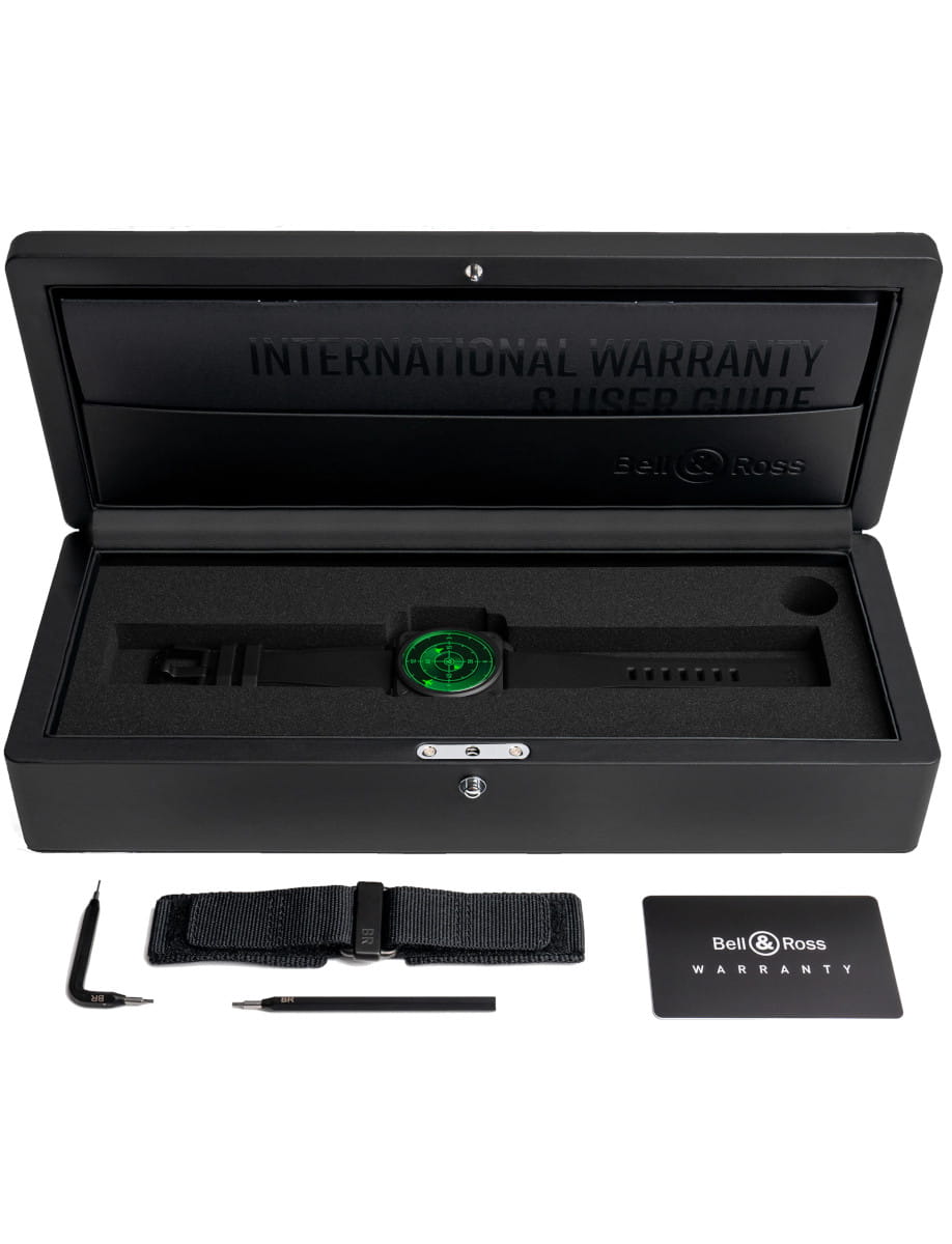 Bell & Ross watch with green dial in a black presentation case, plus extra strap and warranty card nearby.