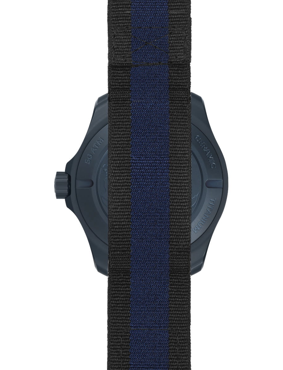 Back view of a blue ceramic watch with a blue and black striped NATO strap, showing the crown on the left side.