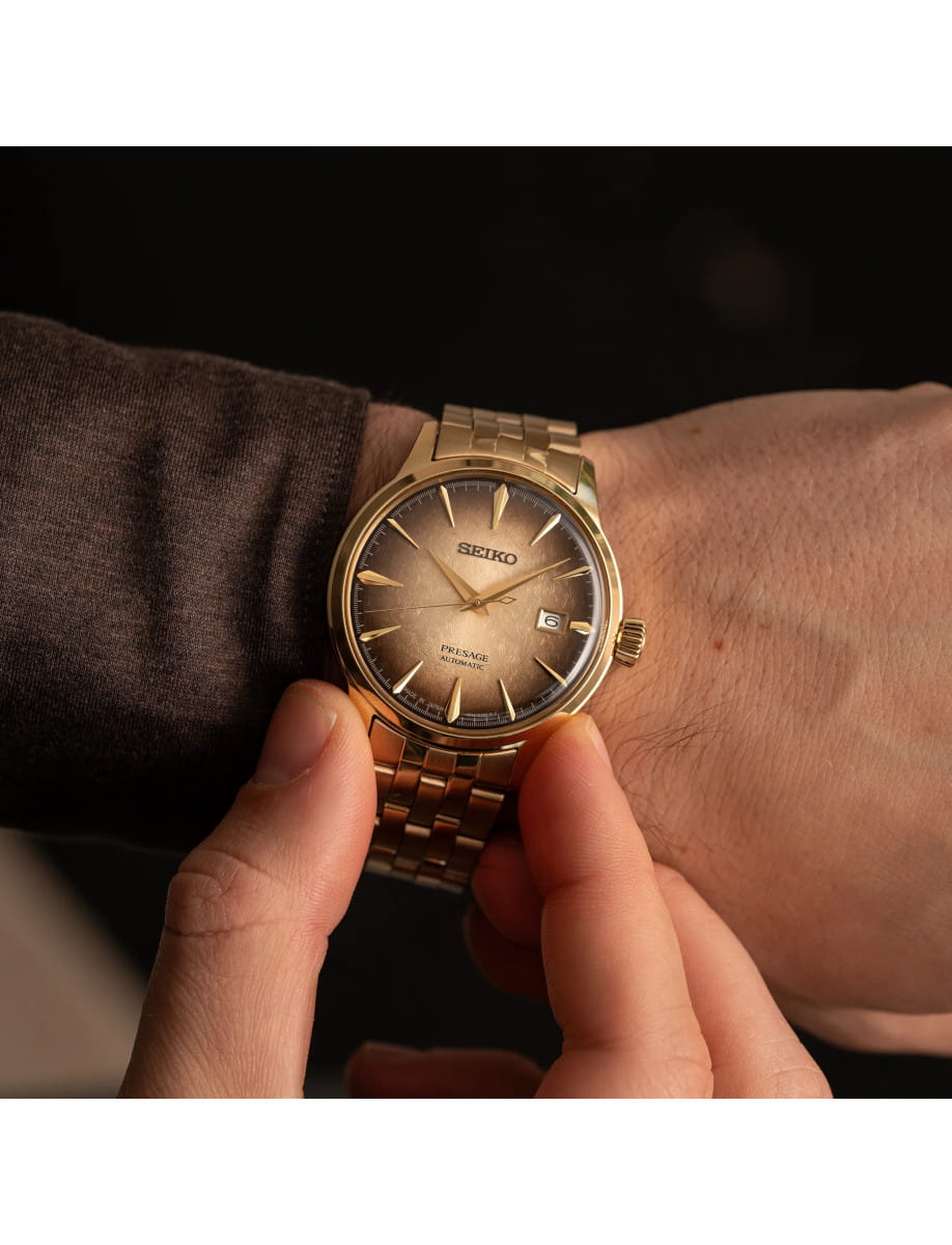 Gold-tone Seiko Presage automatic wristwatch with a brown gradient dial worn on the wrist, showing the date window at 3 o'clock.