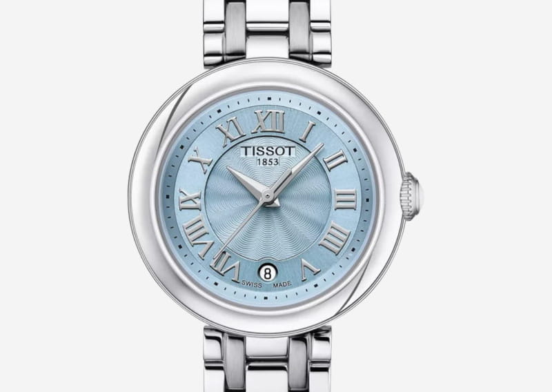 Stainless steel wristwatch with a round blue dial featuring silver Roman numerals and a date window at 6 o'clock, brand Tissot.